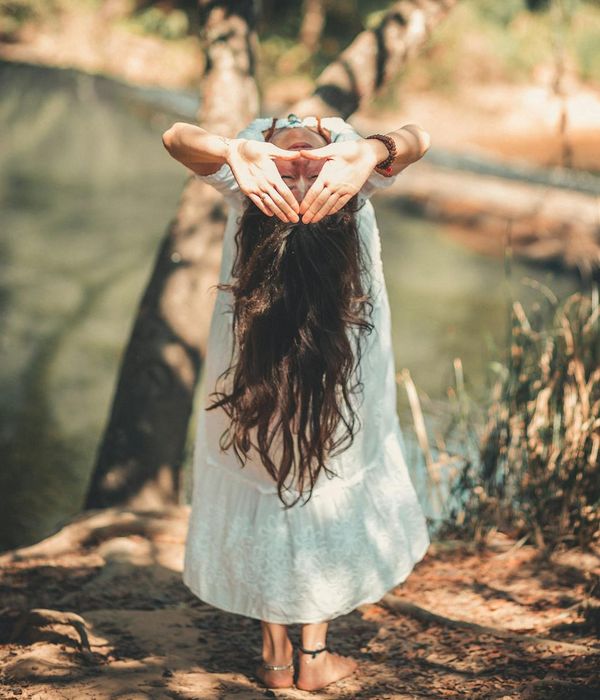 Woman in a peaceful yoga pose in a bright, serene environment.